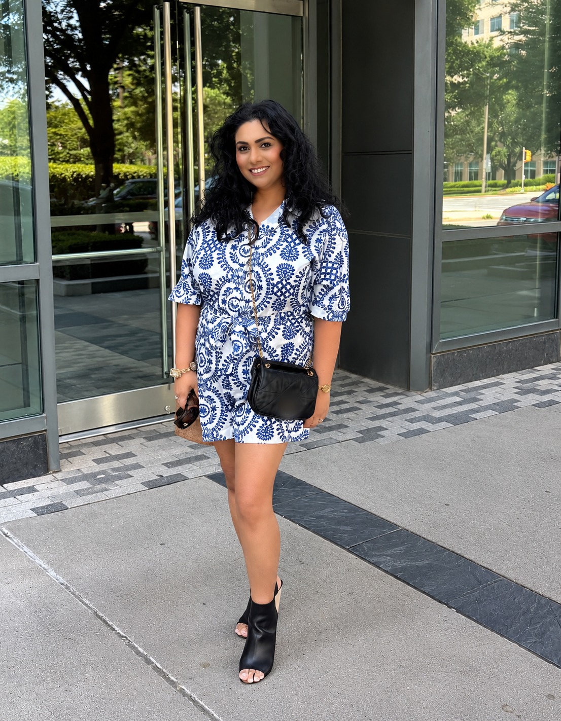 Anabin Islam smiling in a blue and white printed romper outside a glass building