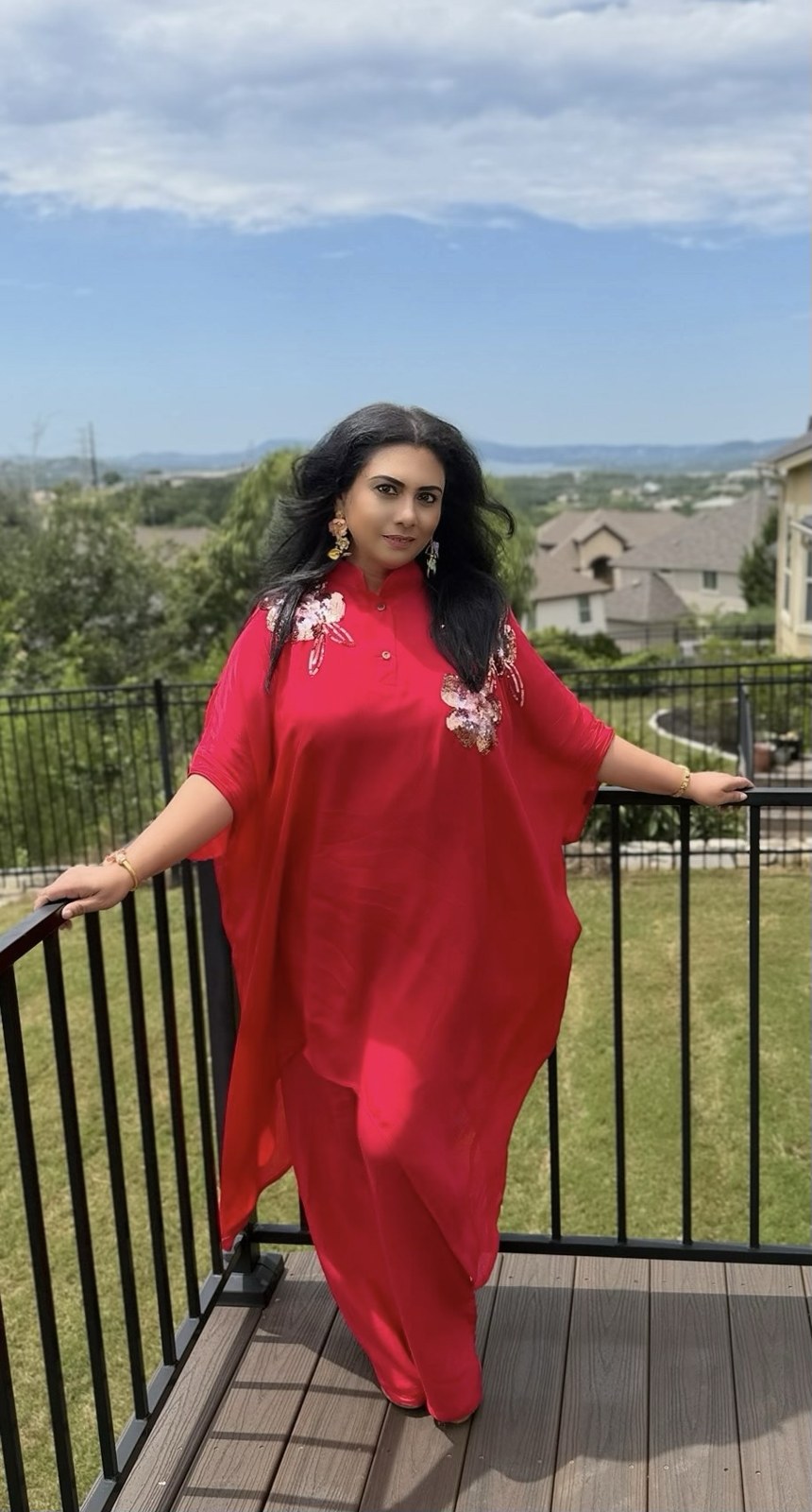 Founder in a red kaftan with floral embellishments on a deck overlooking the hills